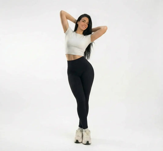 Mujer en ropa deportiva blanca y negra, ideal para entrenamientos y fitness en Colombia